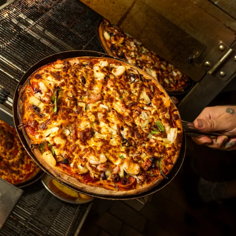 Freshly baked pizza coming out of the oven