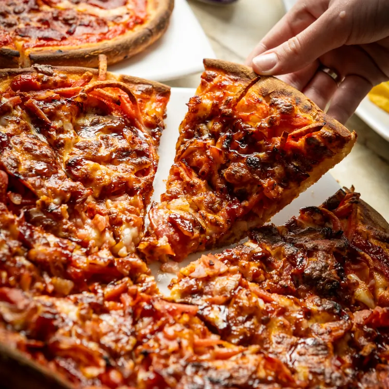 Cheesy pizza slice being pulled from a whole Food Corp pizza