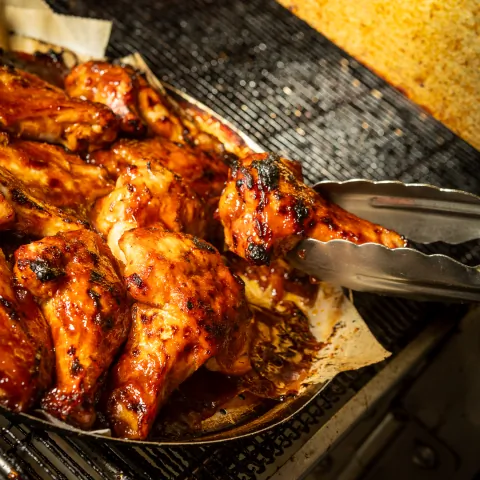 Chicken wings on the grill with tongs