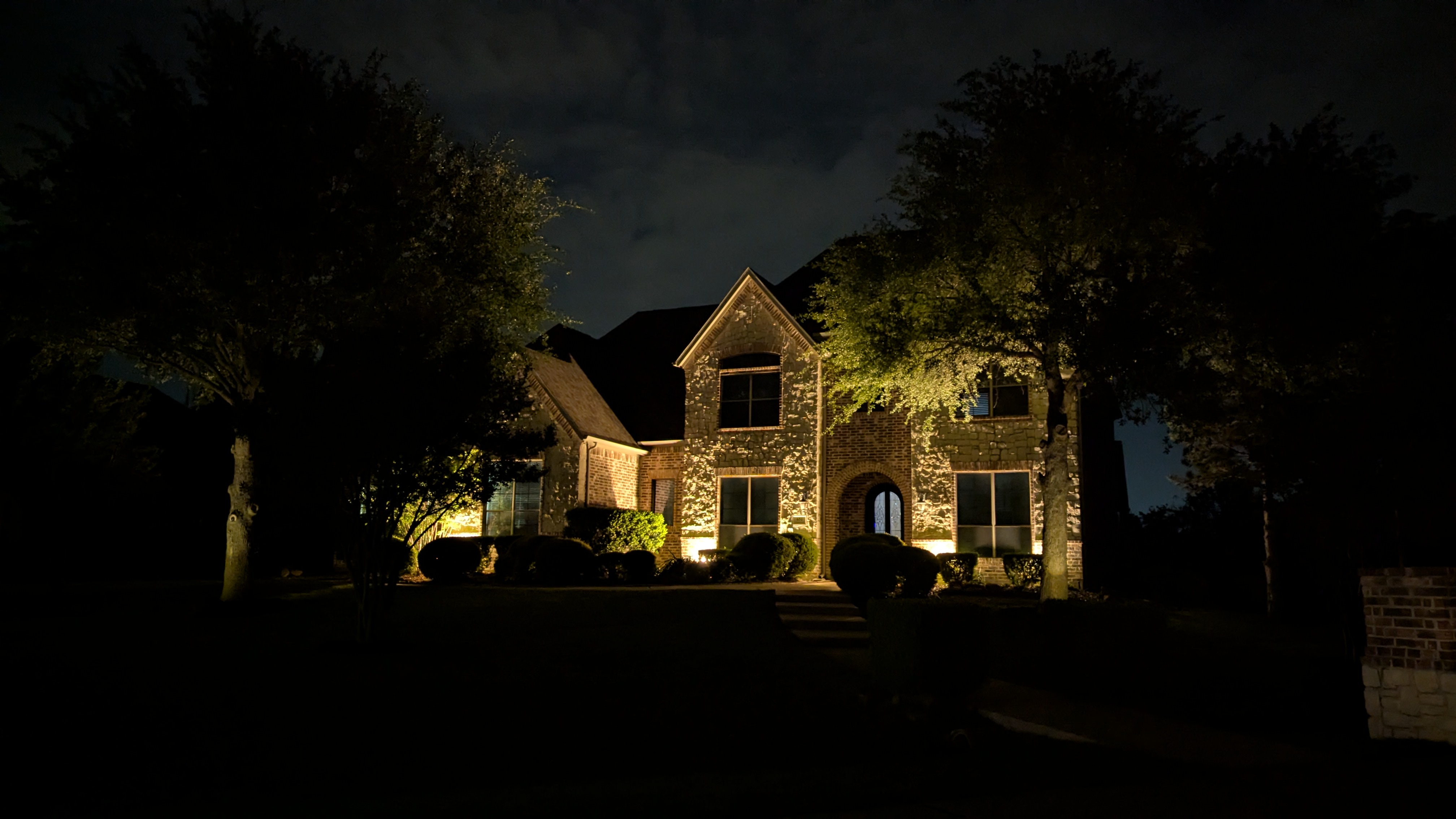 Before landscape lighting redesign, harsh builder-grade lighting