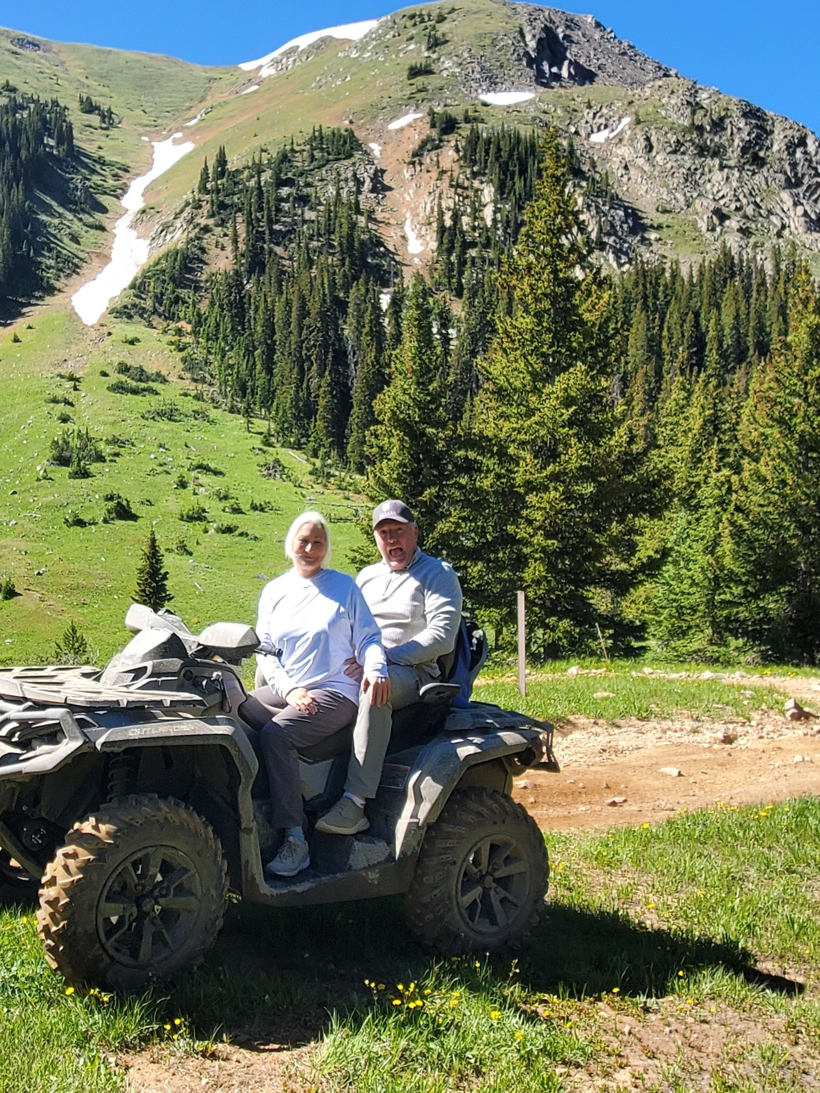 Judy and her husband on an ATV in the mountains