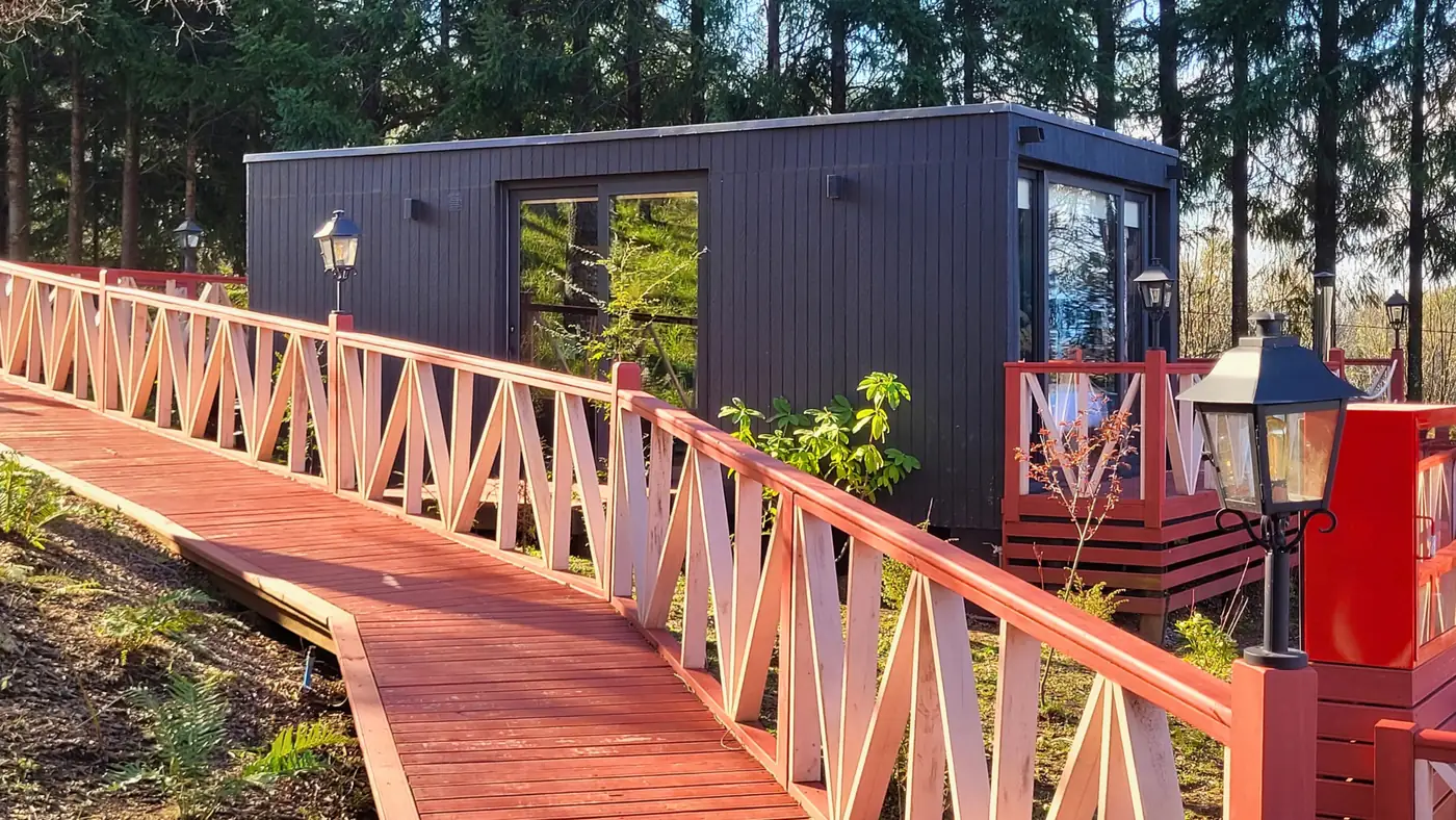 Pasarela con faroles que lleva a la entrada de una tiny house