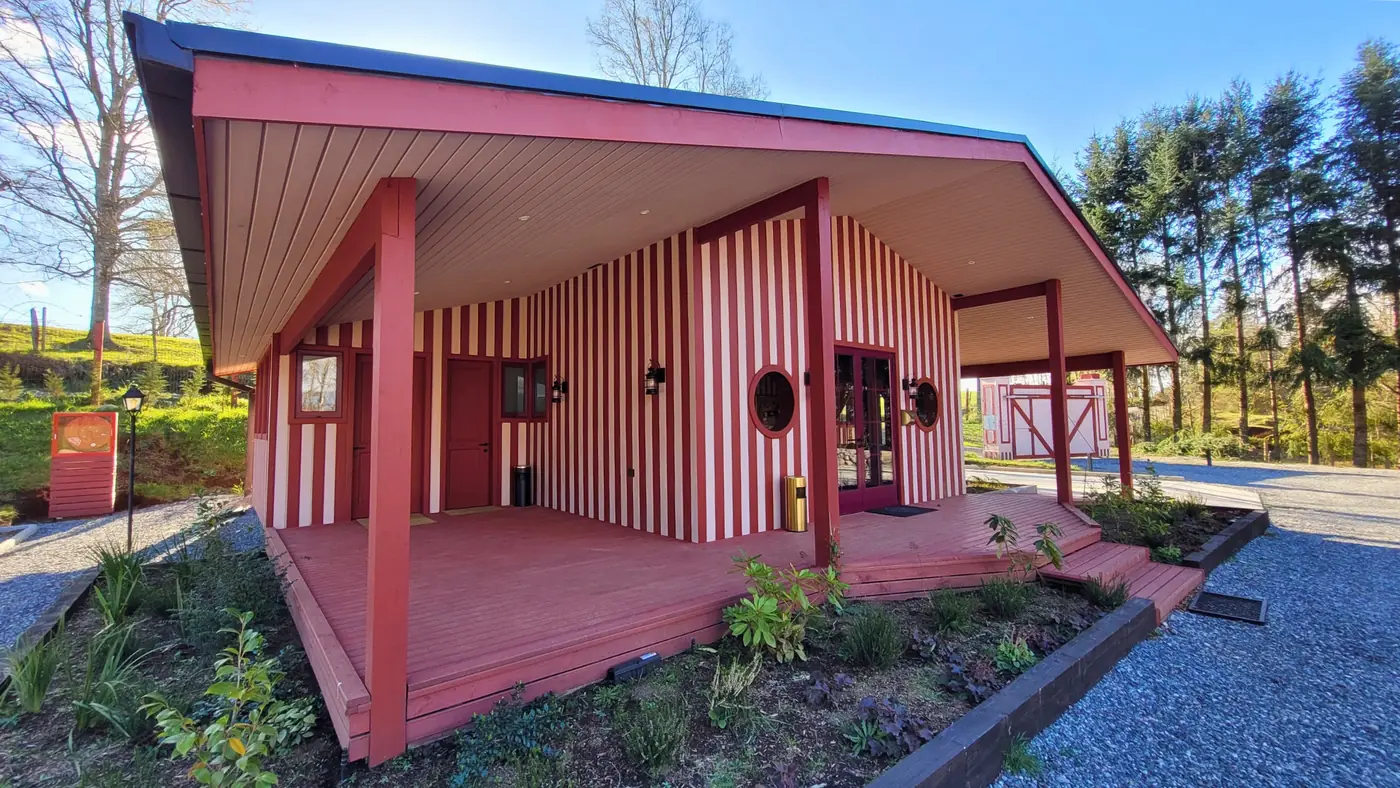 Edificio de recepción de Aslanhaus con fachada a rayas rojas y blancas y terraza techada