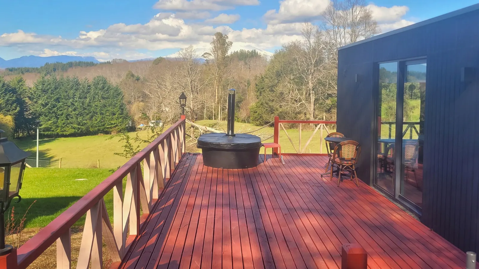 Deck de madera con tinaja caliente y vista a la cordillera en una tiny house de Aslanhaus