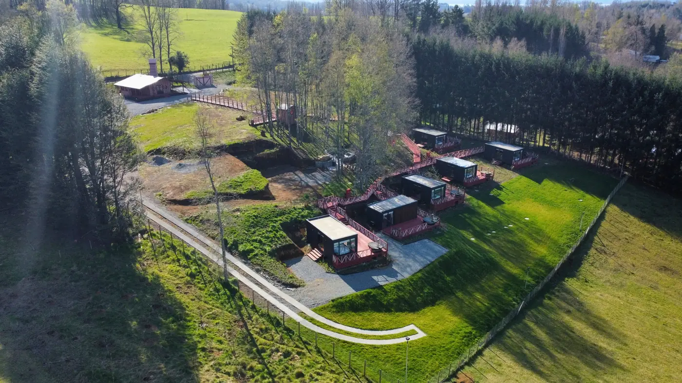Vista aérea de tiny houses con decks junto a la pradera y el bosque