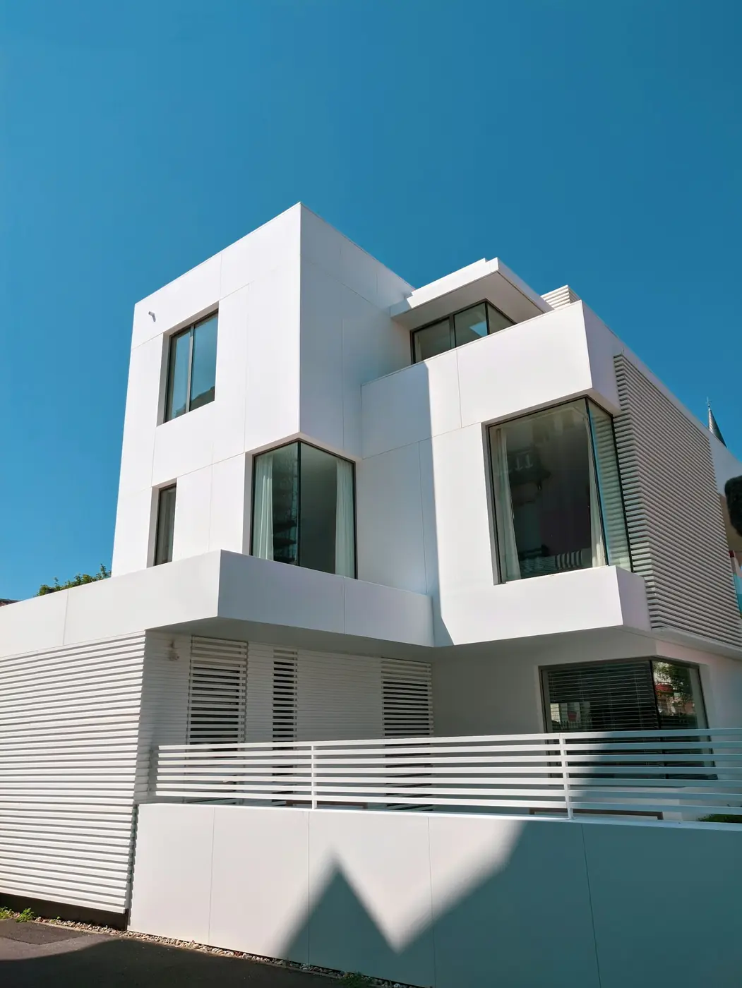 A sculptural white multi-level residential building under clear sky.