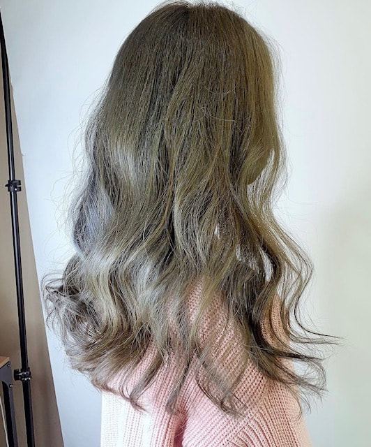 Long brown waves with lighter ribbons against a pale wall.