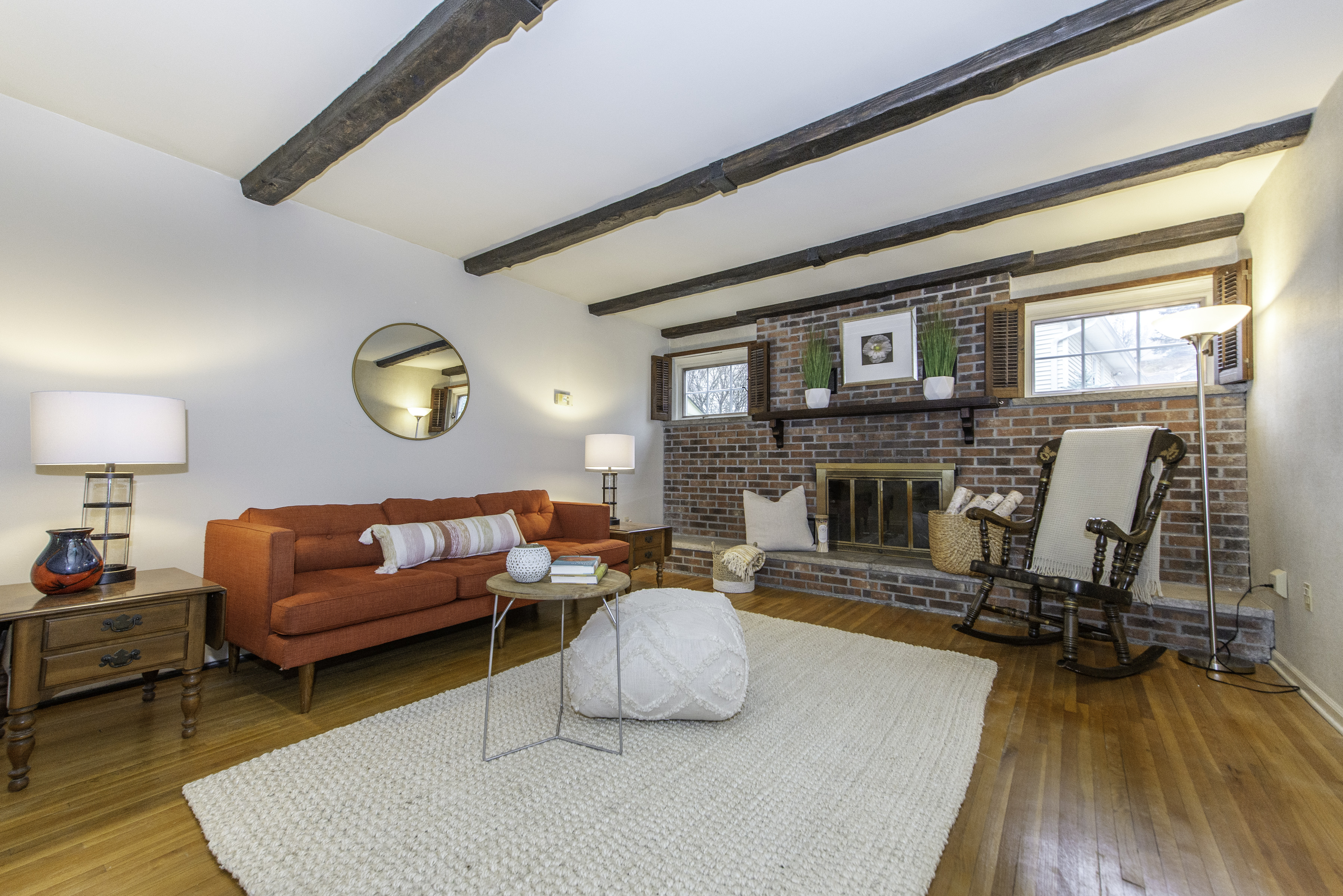 living room in a warm and inviting home with a brick wood burning fireplace and orange couch