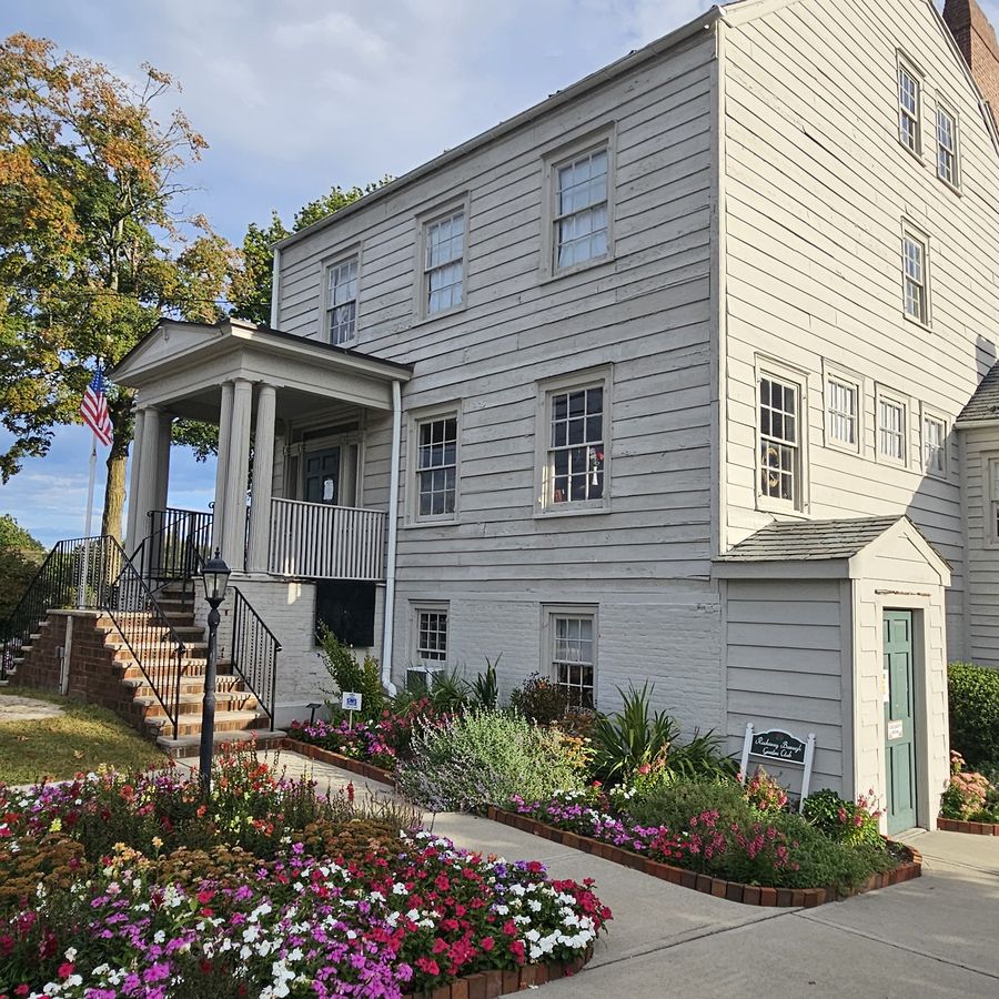 Historic white clapboard building that houses the Rockaway Borough Public Library, with flower gardens
