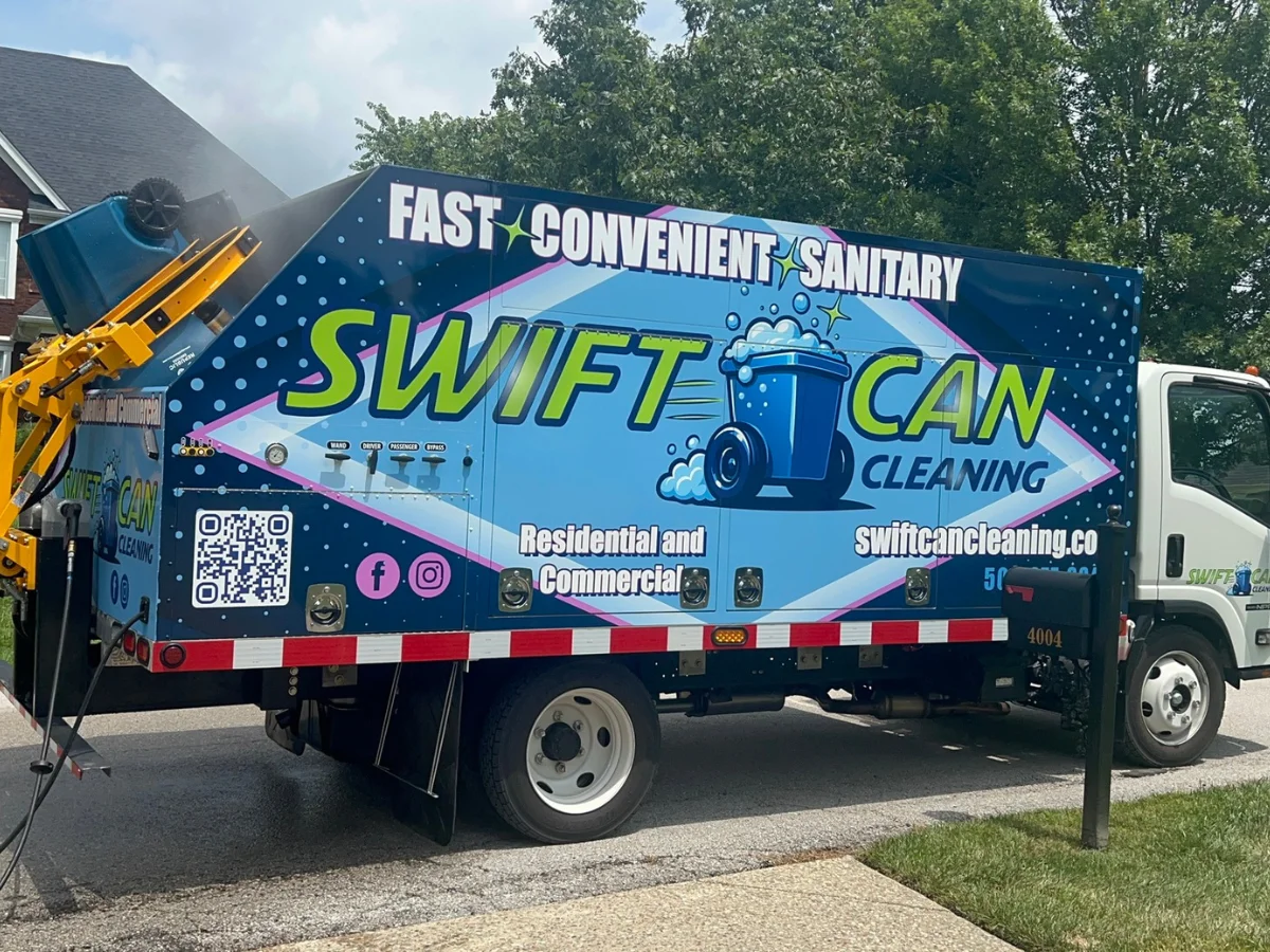 Side view of a Swift Can Cleaning truck with a blue dumpster being cleaned on a sunny day.