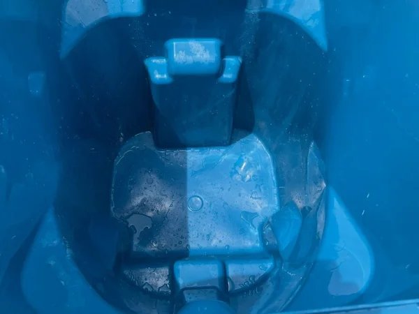 The inside of a vibrant blue plastic bin is visible, featuring water droplets and condensation on its textured surface.
