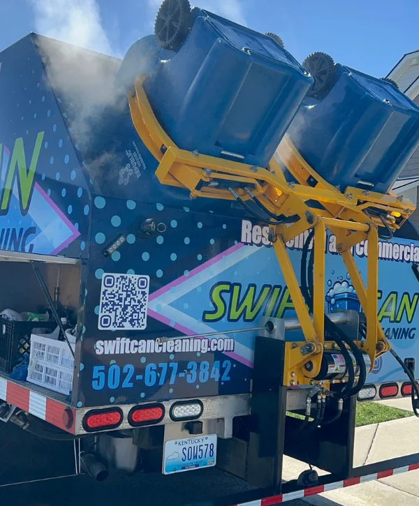 Rear view of a blue and white Swift Can Cleaning truck with a yellow bin lift mechanism, parked on a residential street.