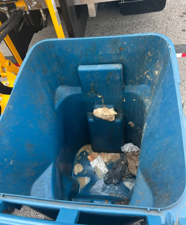 Close-up inside a dirty, textured blue plastic bin with traces of brown debris and worn surfaces.