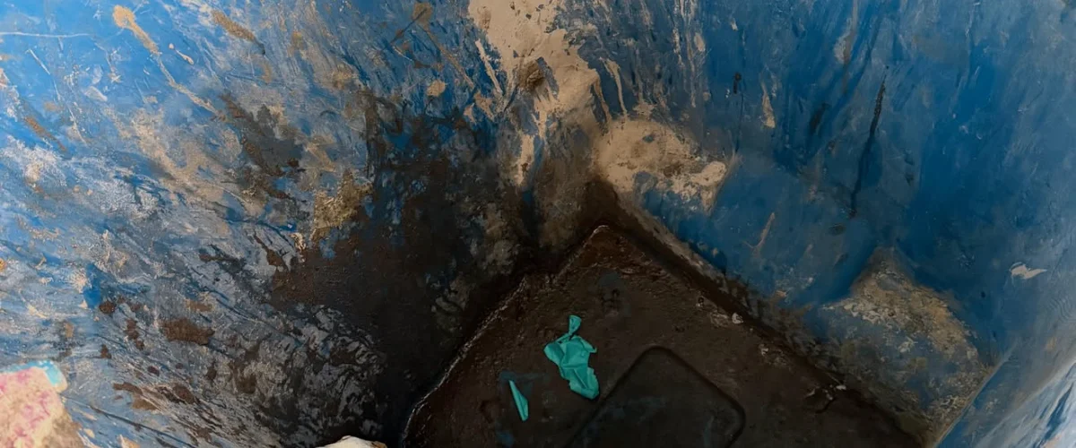 A close-up, high-angle view looking down into a dirty blue trash can with various garbage and liquid residue inside. A close-up, high-angle view looking down into a dirty blue trash can with various garbage and liquid residue inside.