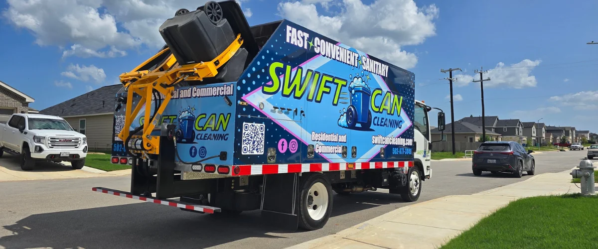 A Swift Can Cleaning sanitation truck on a residential street with a trash bin being lifted for cleaning, under a blue sky. A Swift Can Cleaning sanitation truck on a residential street with a trash bin being lifted for cleaning, under a blue sky.
