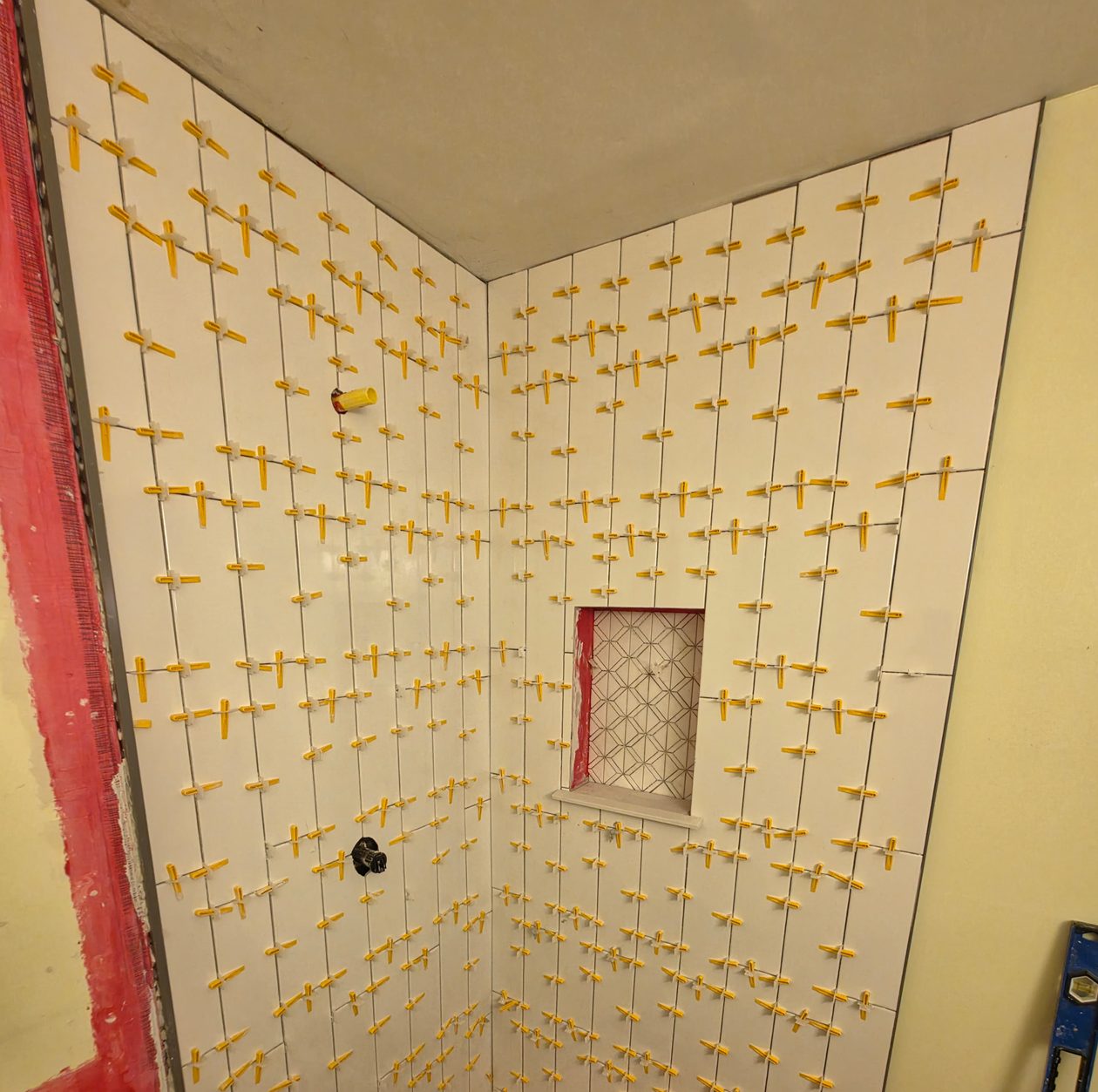 Vertical shower wall tile and a patterned niche being aligned with spacers.
