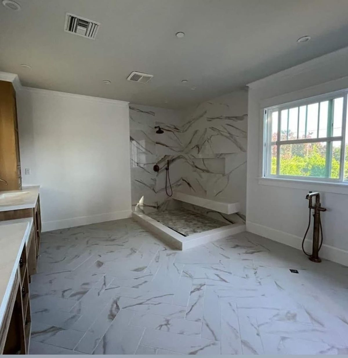 Bright bathroom with a tiled walk-in shower, large-format floor tile, and freestanding tub filler.