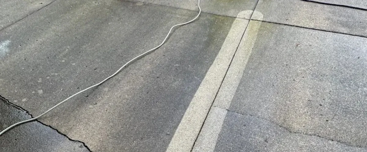 Concrete driveway showing dramatic difference between cleaned and dirty sections after power washing.