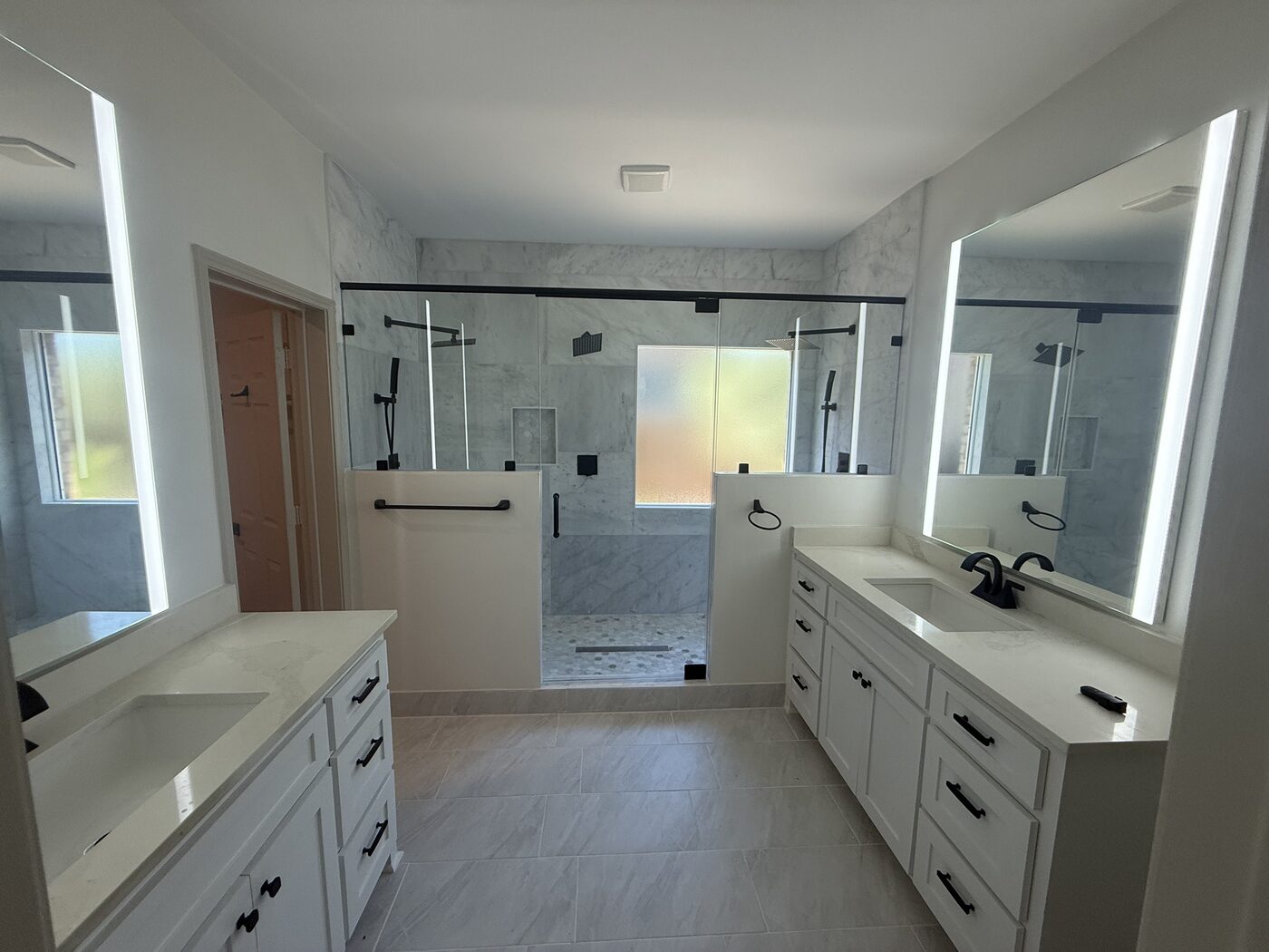 Finished master bathroom with double vanity and glass shower after fire rebuild