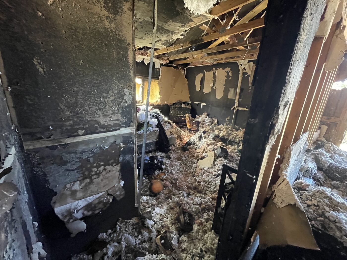 Charred interior with burned framing and collapsed ceiling after house fire