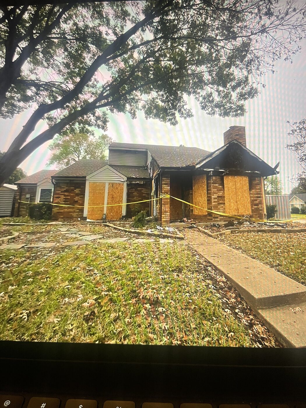 Fire-damaged home exterior in Coppell, TX with boarded windows and caution tape