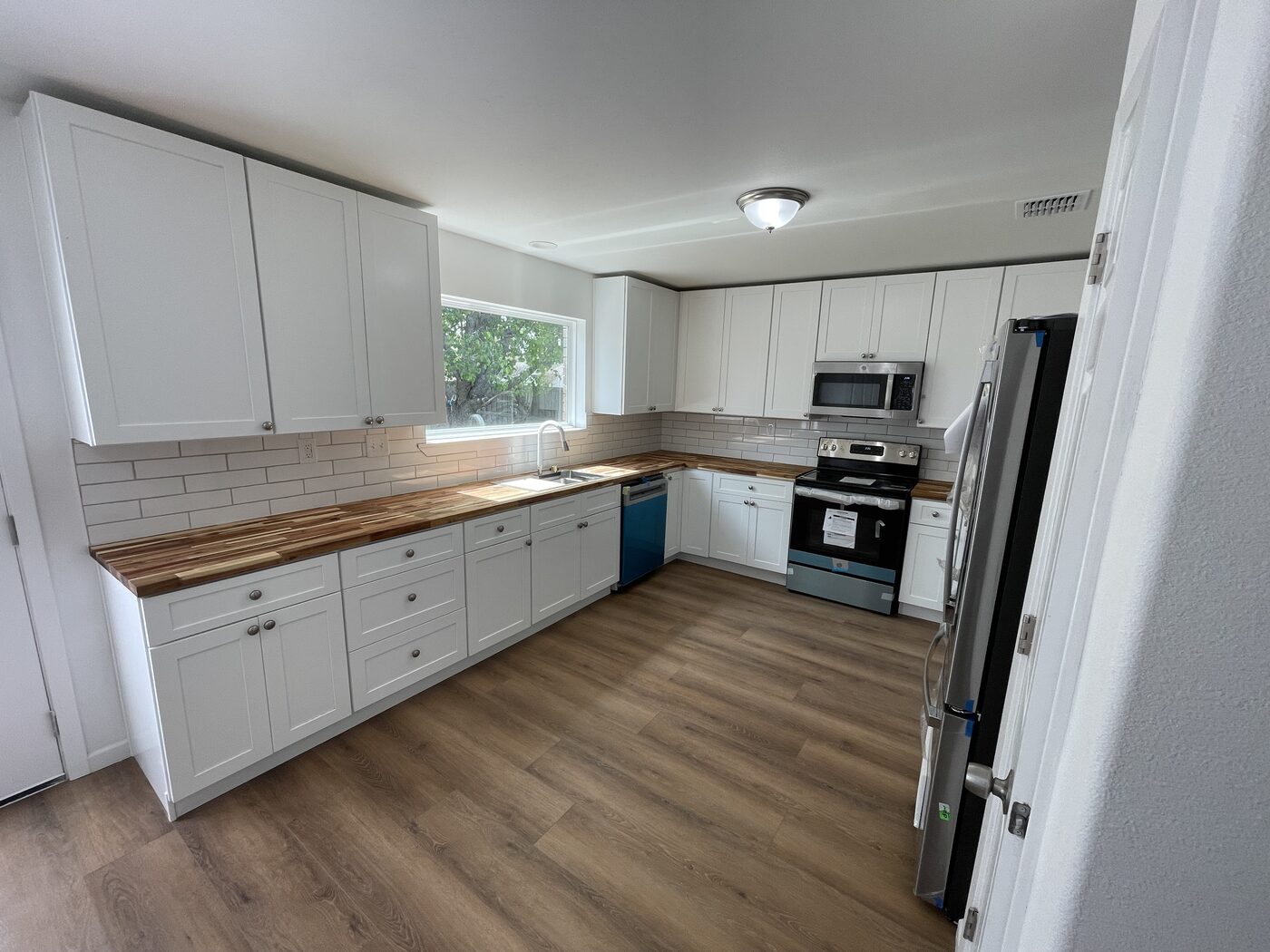 Rebuilt kitchen in Coppell, TX with white shaker cabinets, butcher block counters, and new appliances