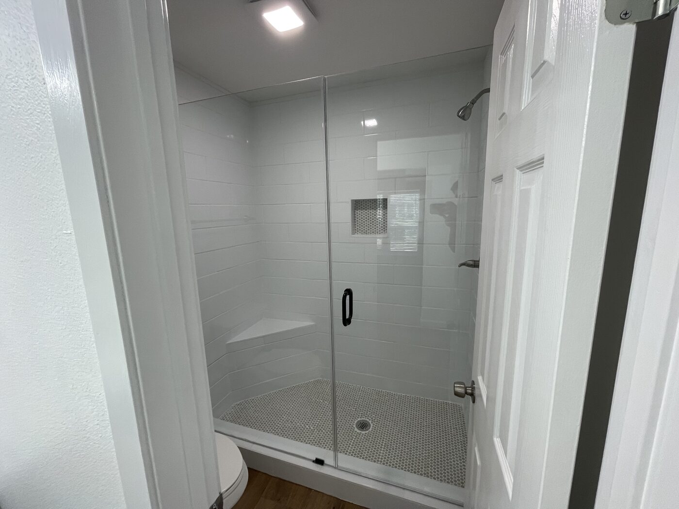 Finished tiled walk-in shower with glass door after fire rebuild