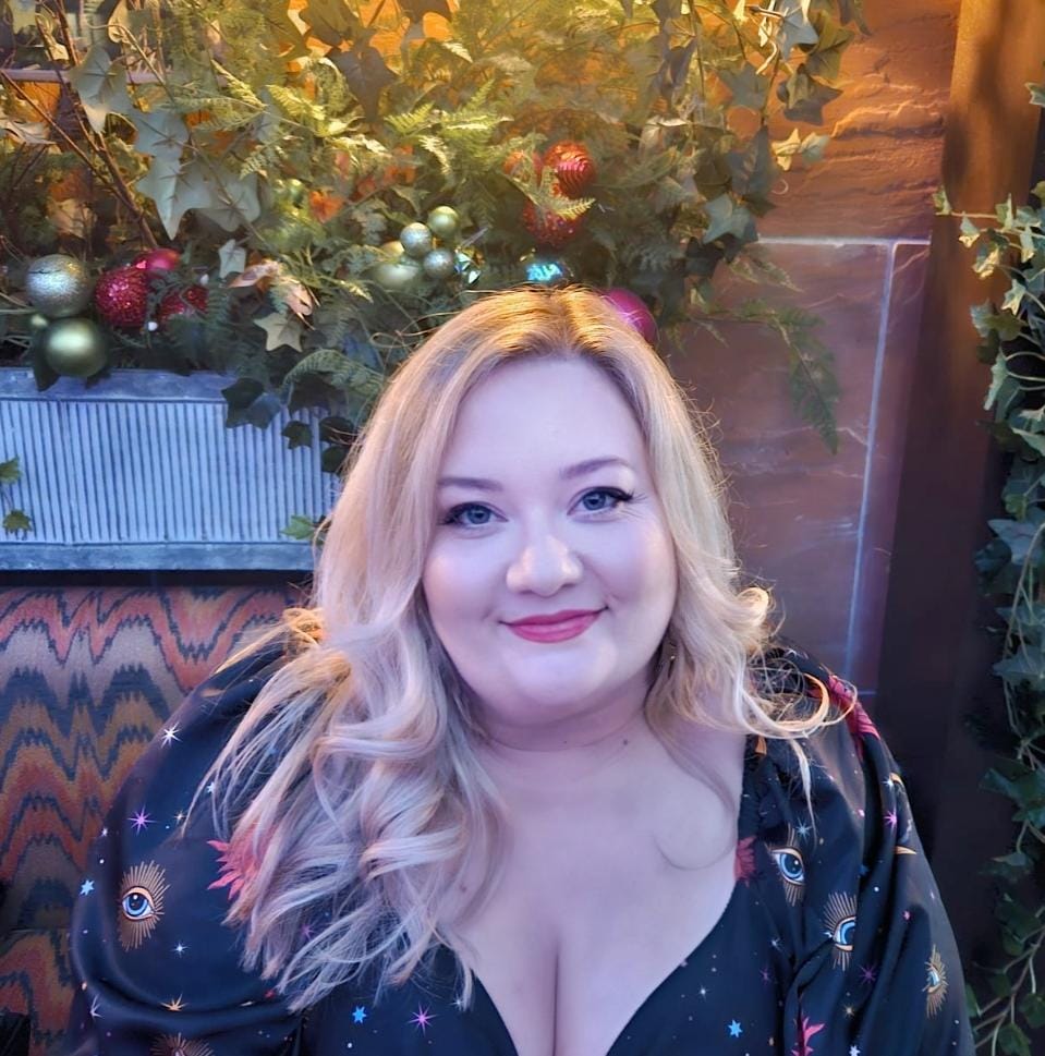Kerri, Psychic and Medium, seated in a black celestial print blouse