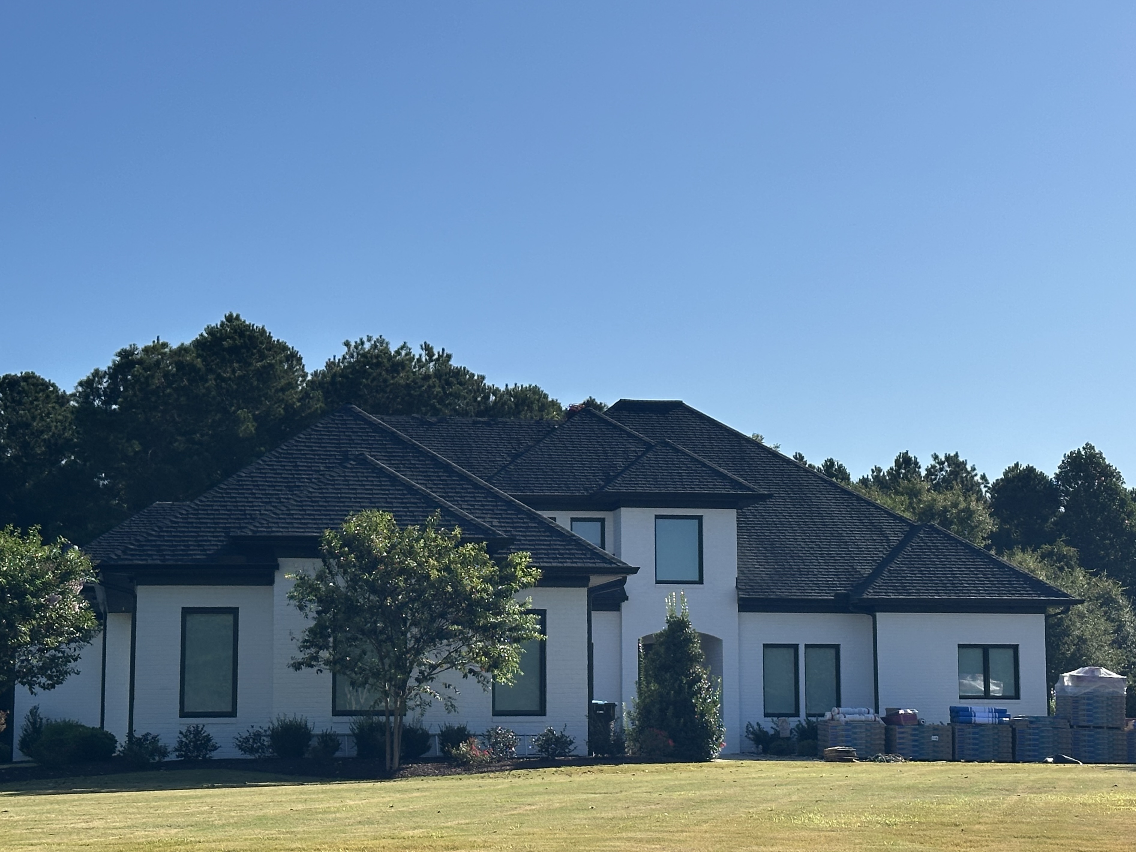 Two-story home with a dark shingle roof against a clear blue sky