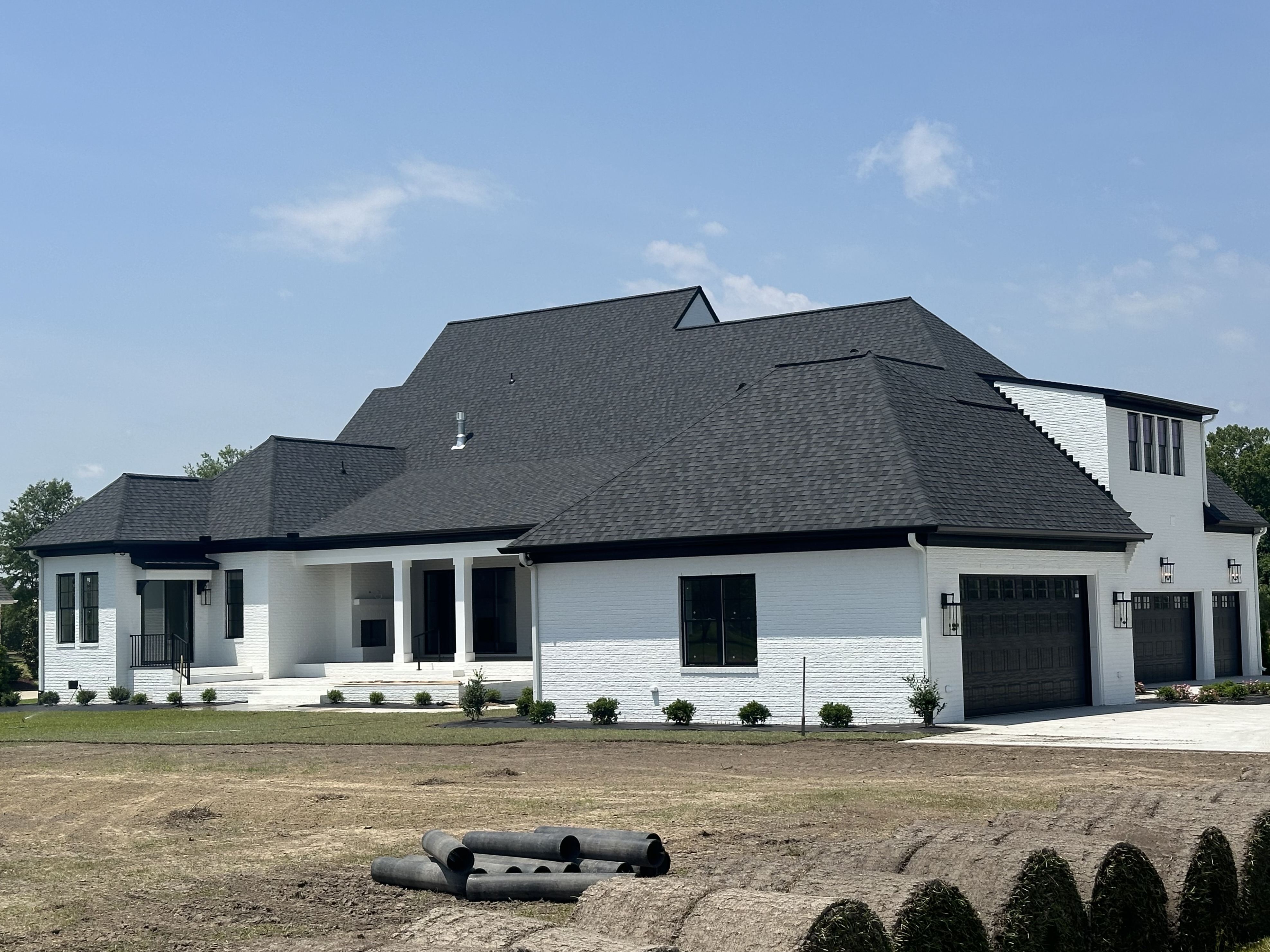 White brick home with a new dark architectural shingle roof