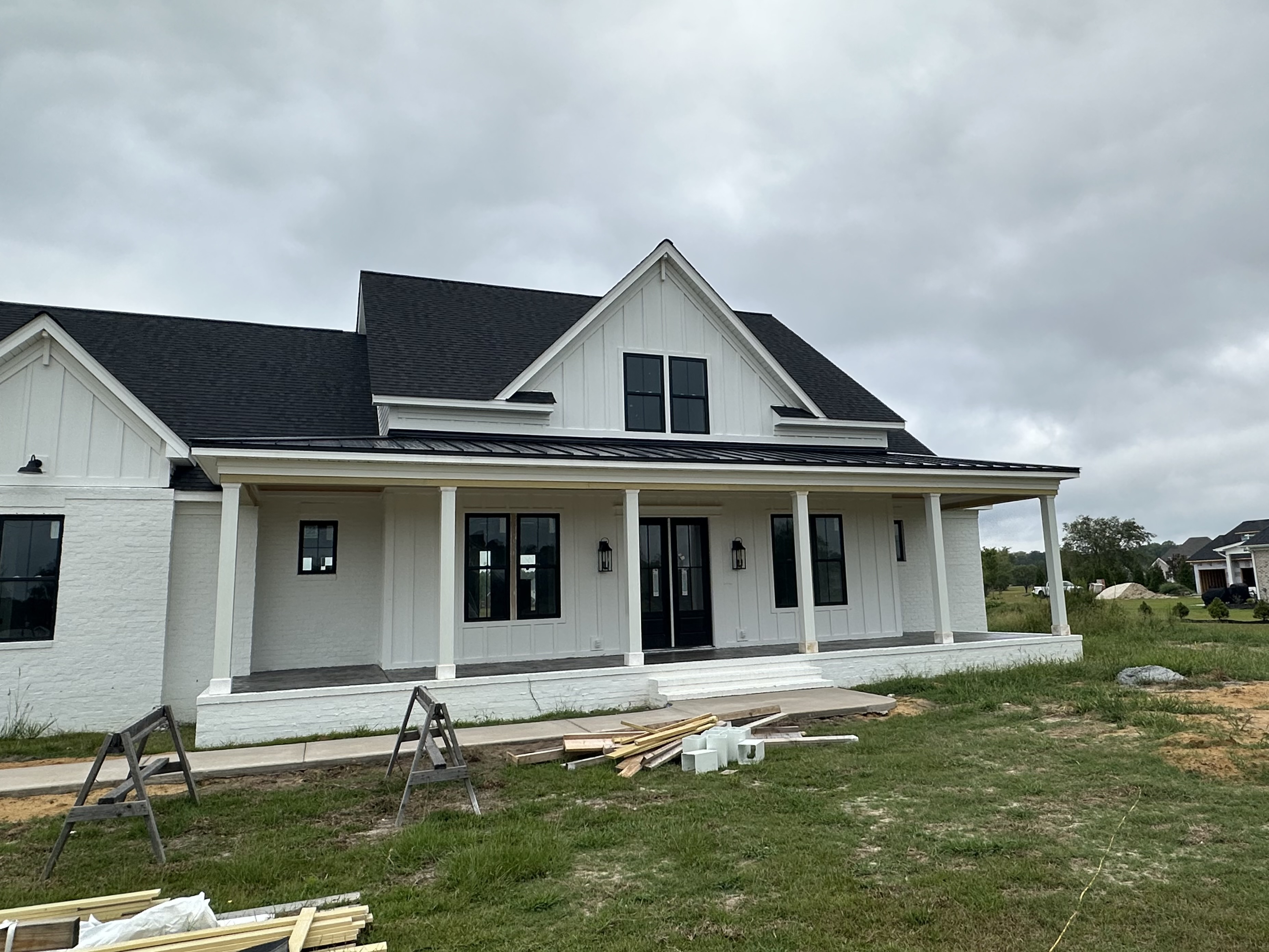 White farmhouse with a new black shingle roof and full front porch