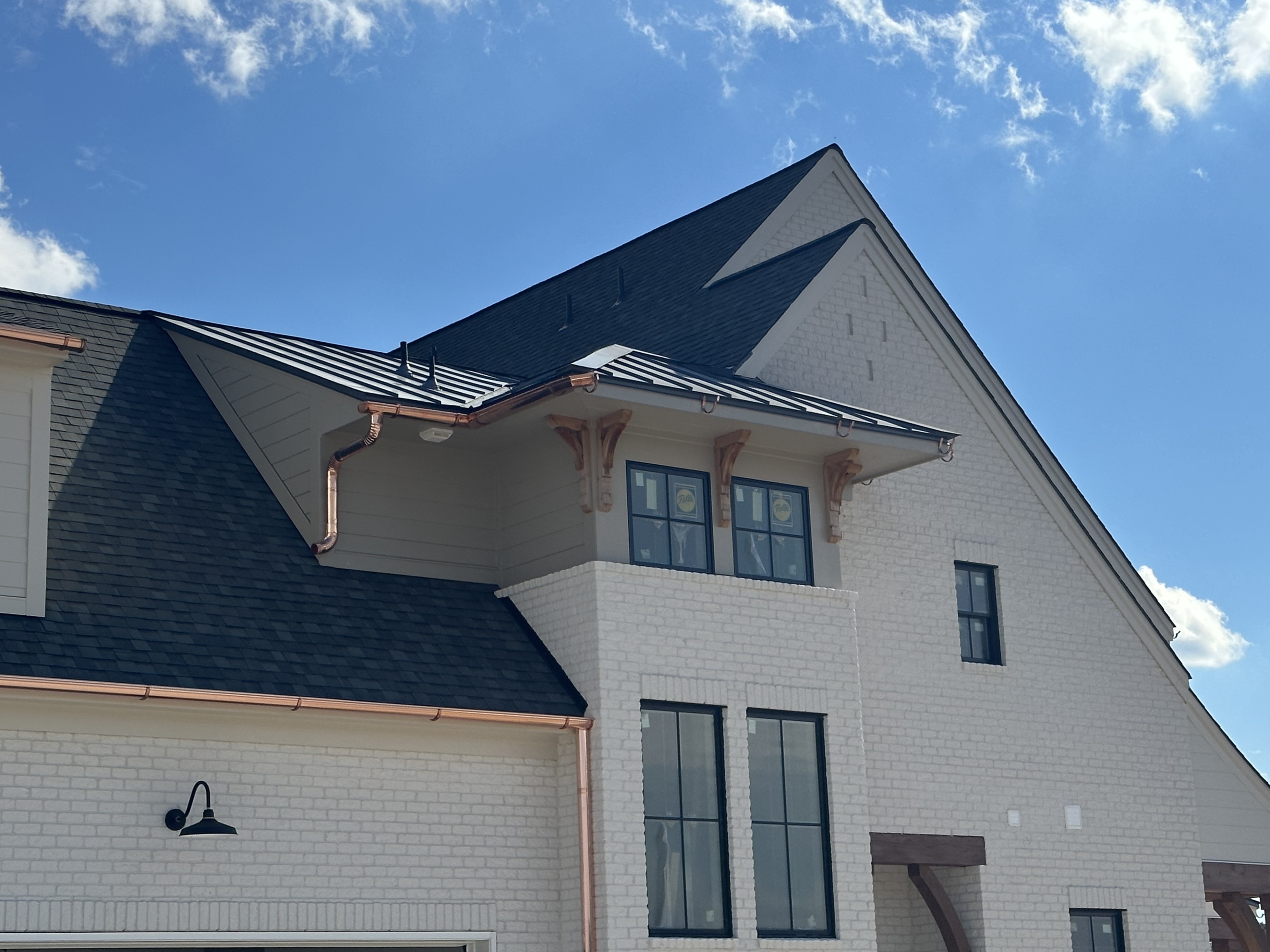 White brick home with a new dark shingle roof under a blue sky