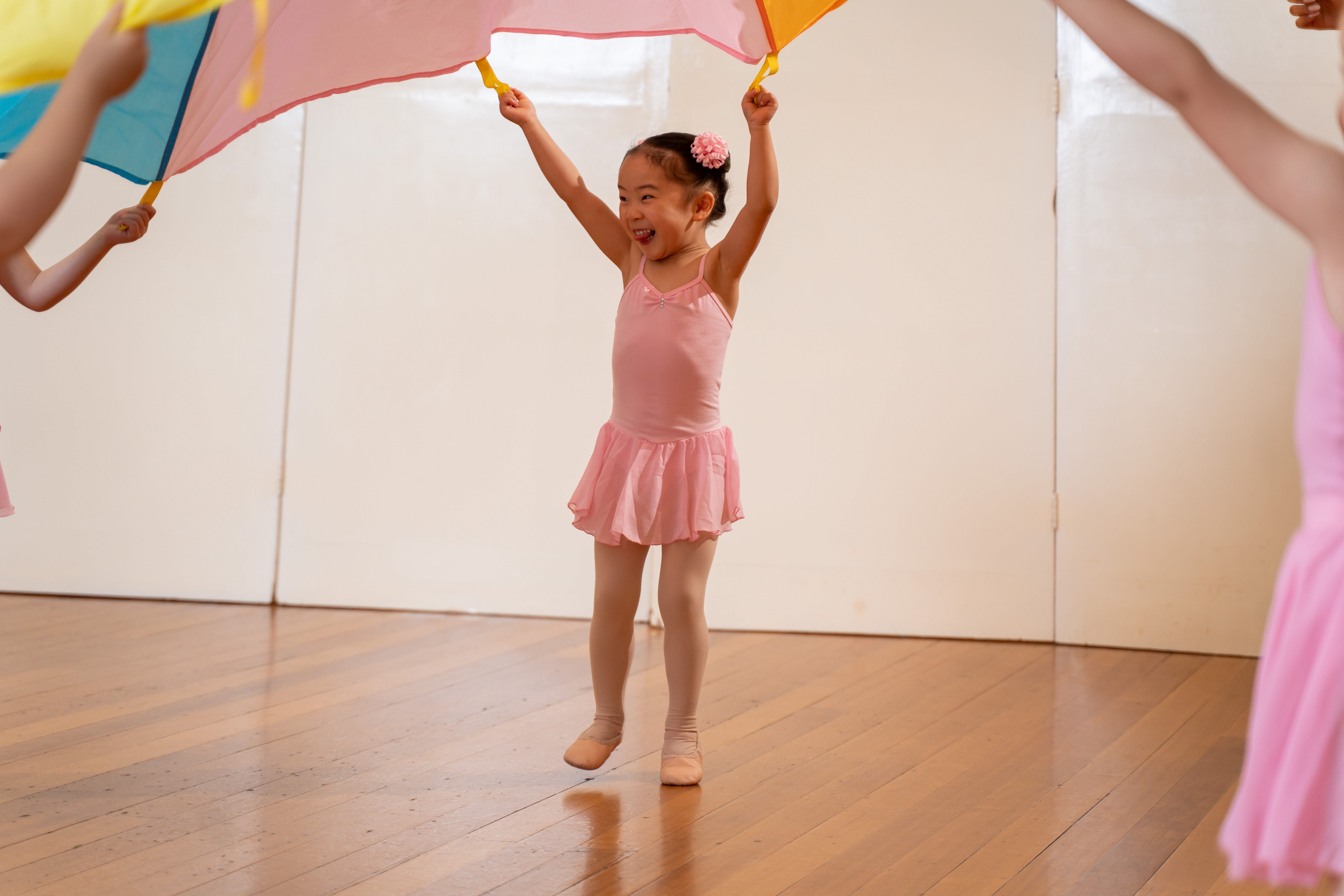 Children dancing joyfully with colourful parachute