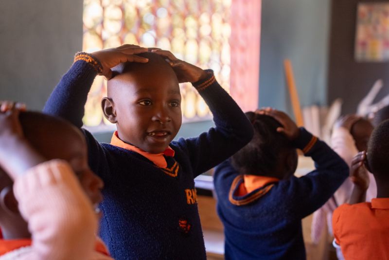 Kids in class with hands on heads