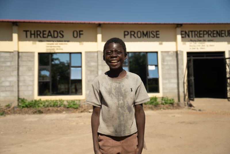 A boy outside Threads of Promise