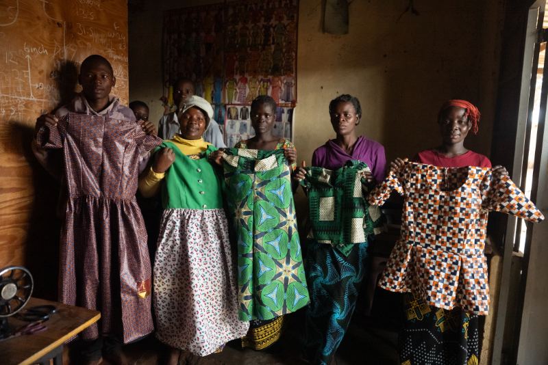 Women showing handmade dresses at a nonprofit program in Malawi