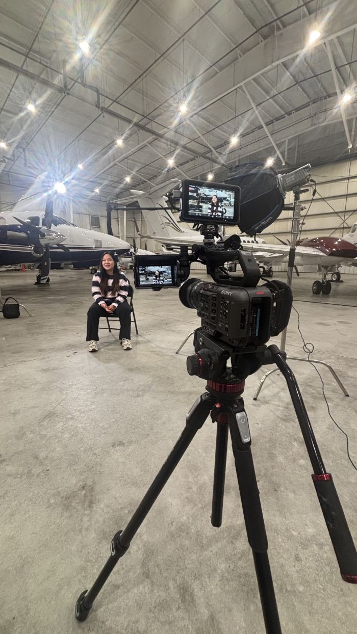 Camera on a tripod filming an interview in a hangar