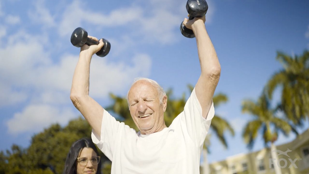 Older adult lifting dumbbells outdoors in a Cynder Media video