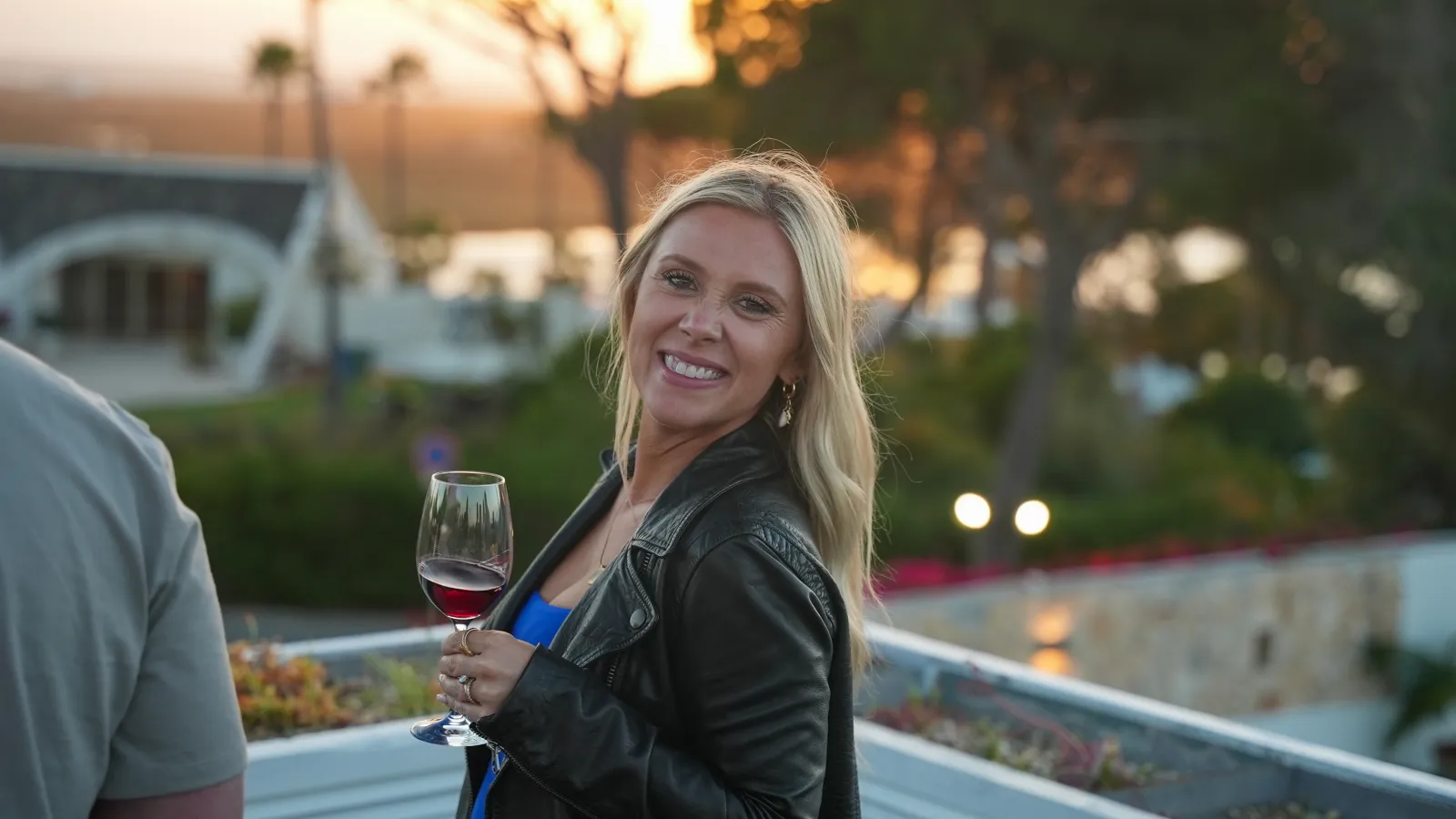 An HPN associate toasting with wine on a terrace at golden hour — President's Club Portugal