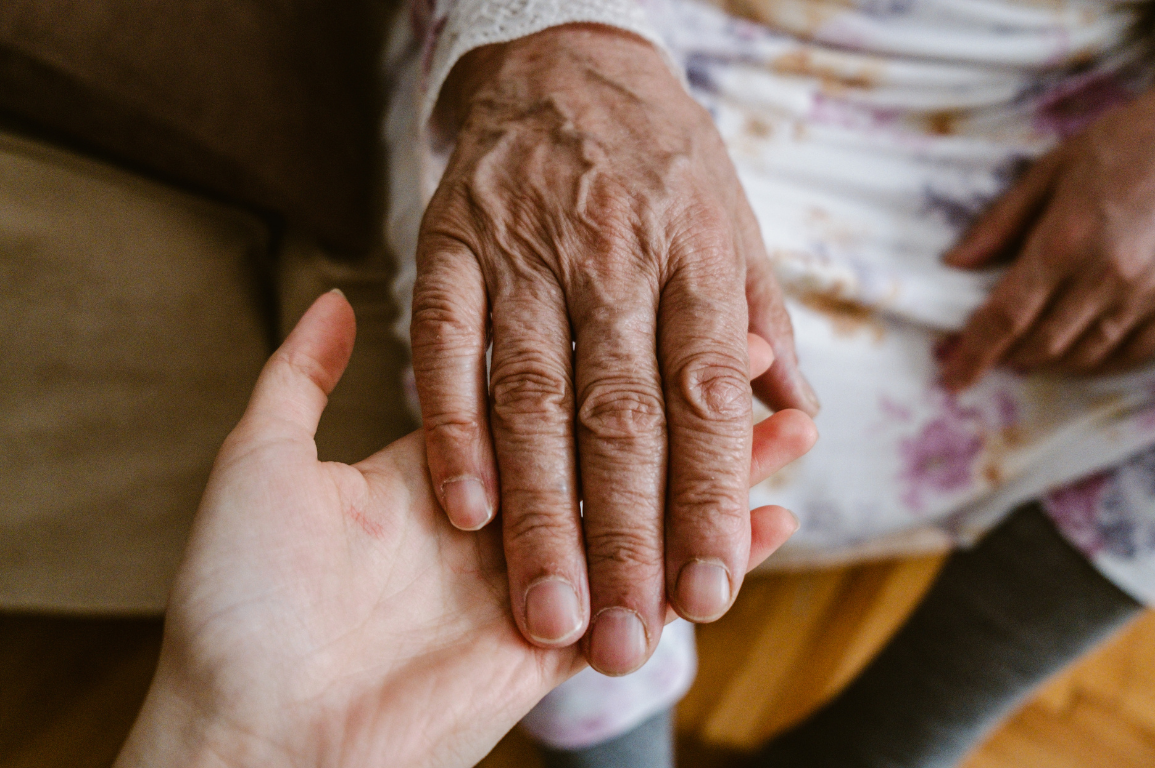An older woman and her adult daughter sitting together on a sofa at home