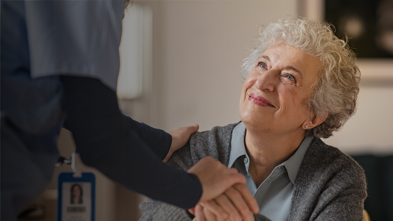 A clinician smiling with her arm around an older woman