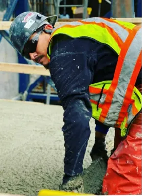 Construction worker in safety gear smoothing wet concrete during a job in Calgary for Vancal Concrete LTD.