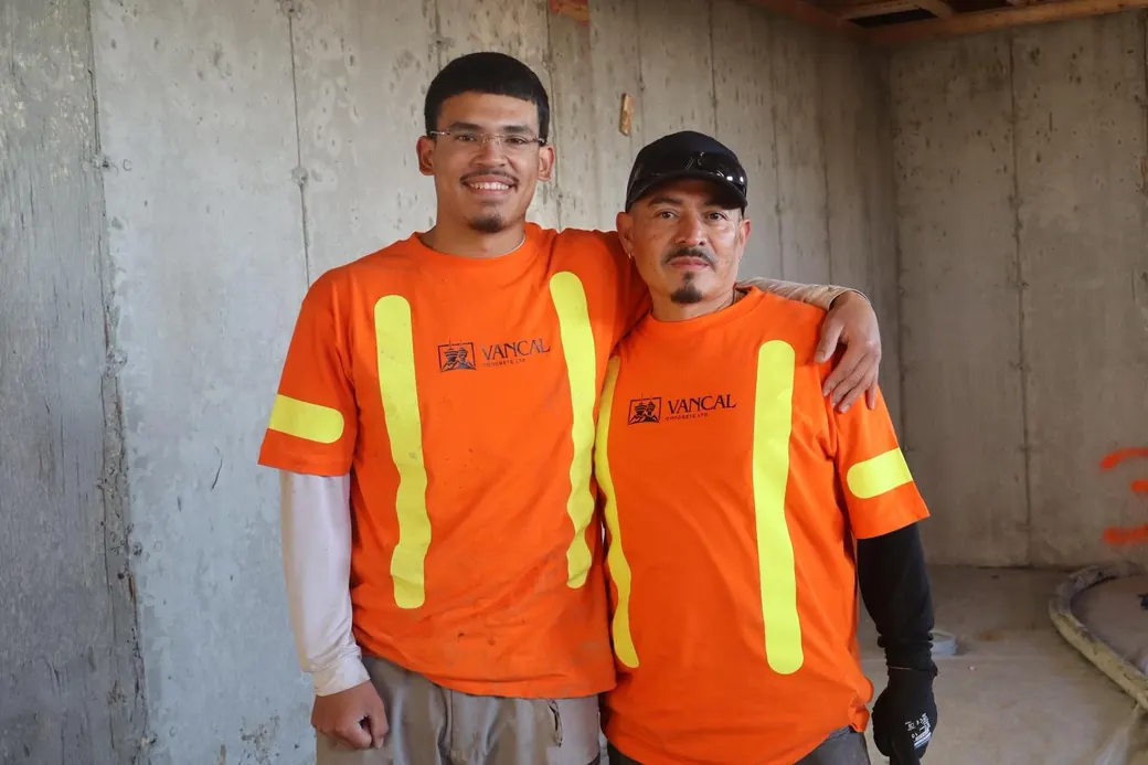 Two Vancal Concrete LTD team members in high-visibility uniforms standing together at a Calgary job site.