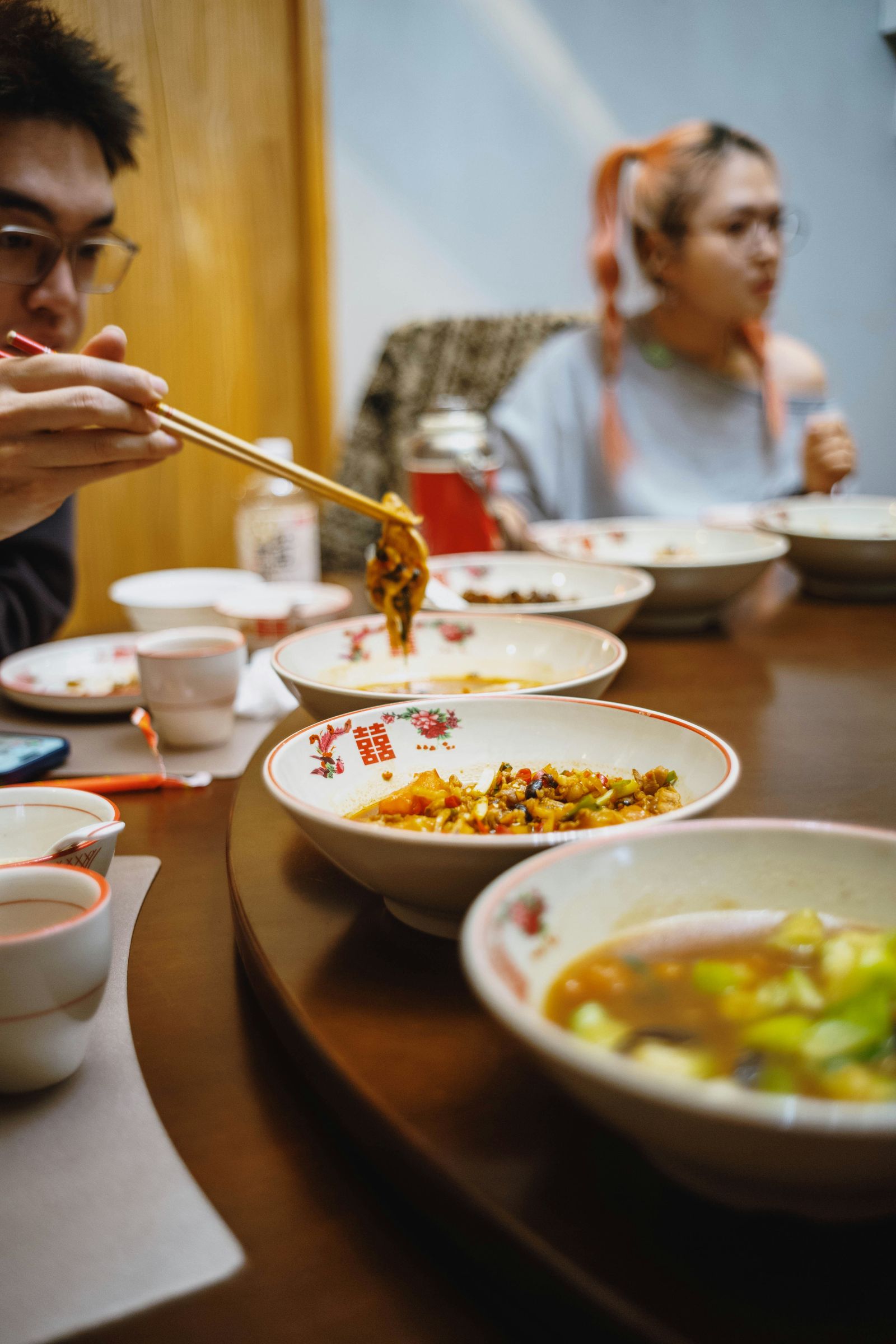 年轻人围着圆桌用筷子夹菜