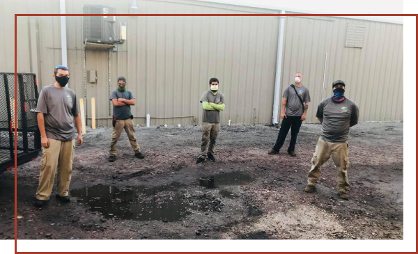 A commercial landscaping crew on a jobsite in Sarasota, posing for a picture in front of a commercial building.