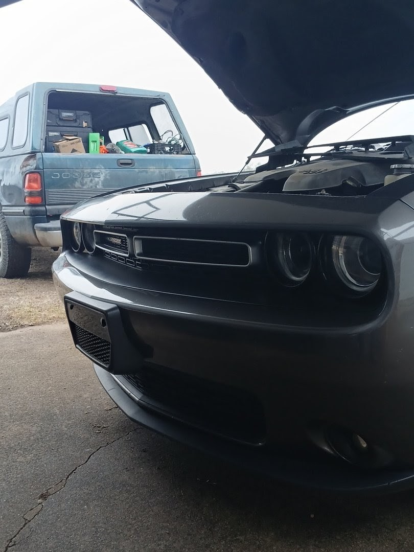 Dodge Challenger being serviced on-site by Honest Joe's Auto mobile mechanic in Bastrop County, TX, with service truck visible in background