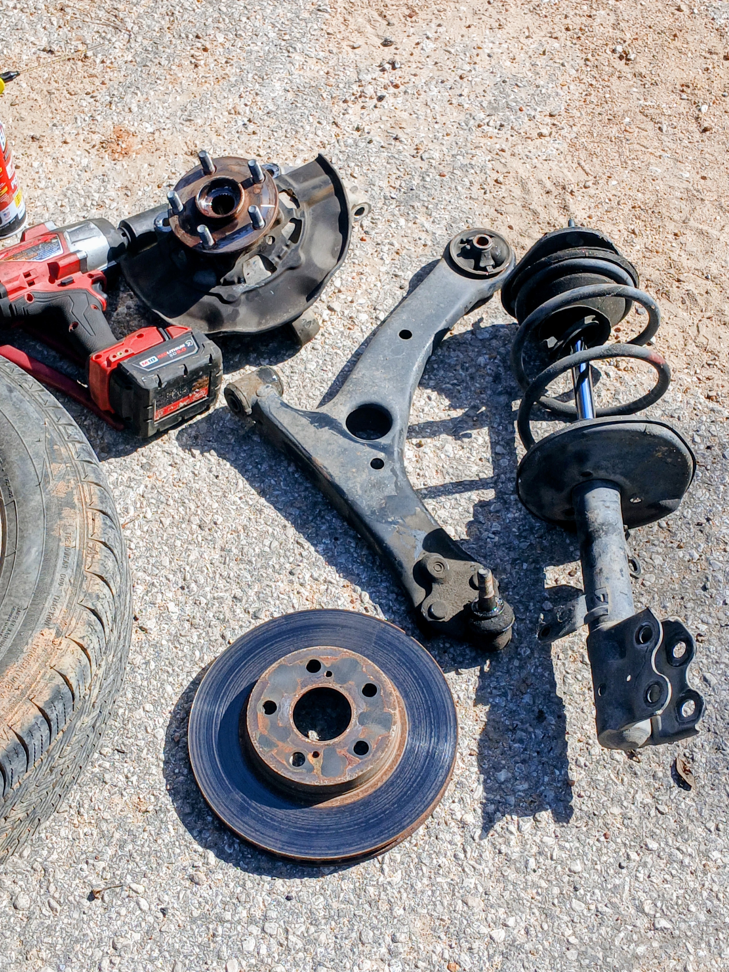 Worn brake rotor and front-end hardware removed during a mobile brake repair