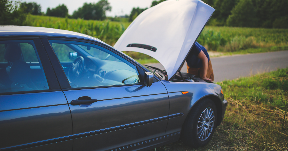 Driver inspecting a car with its bonnet open after a possible mechanical problem.