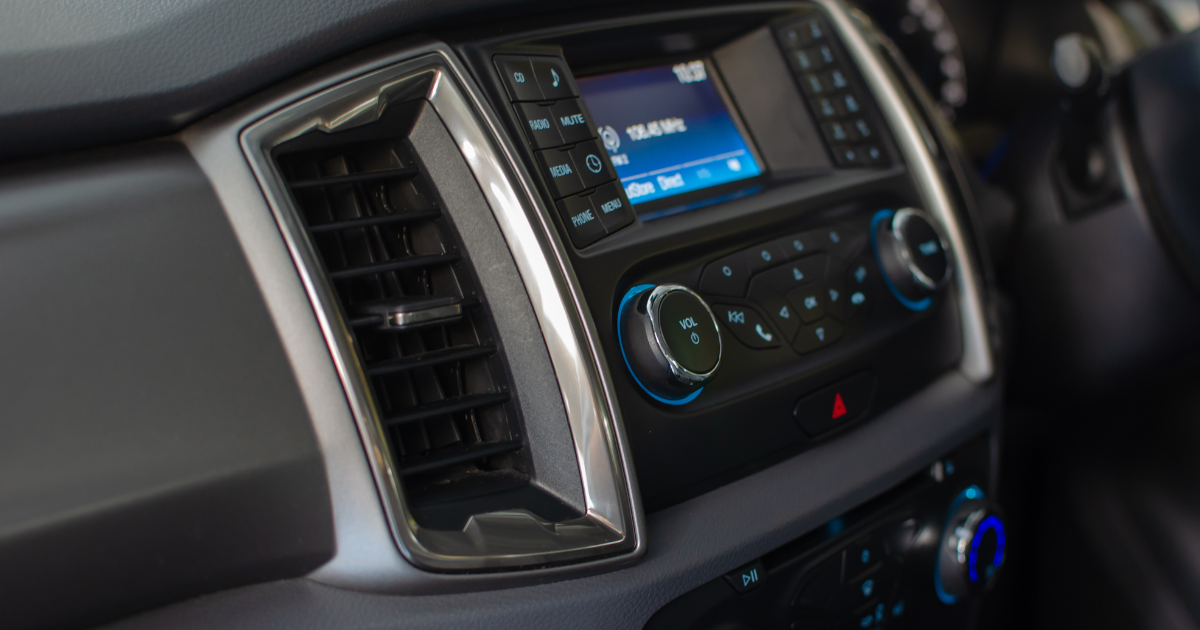 Close-up of a car's dashboard air vent and air conditioning controls on a summer road trip.