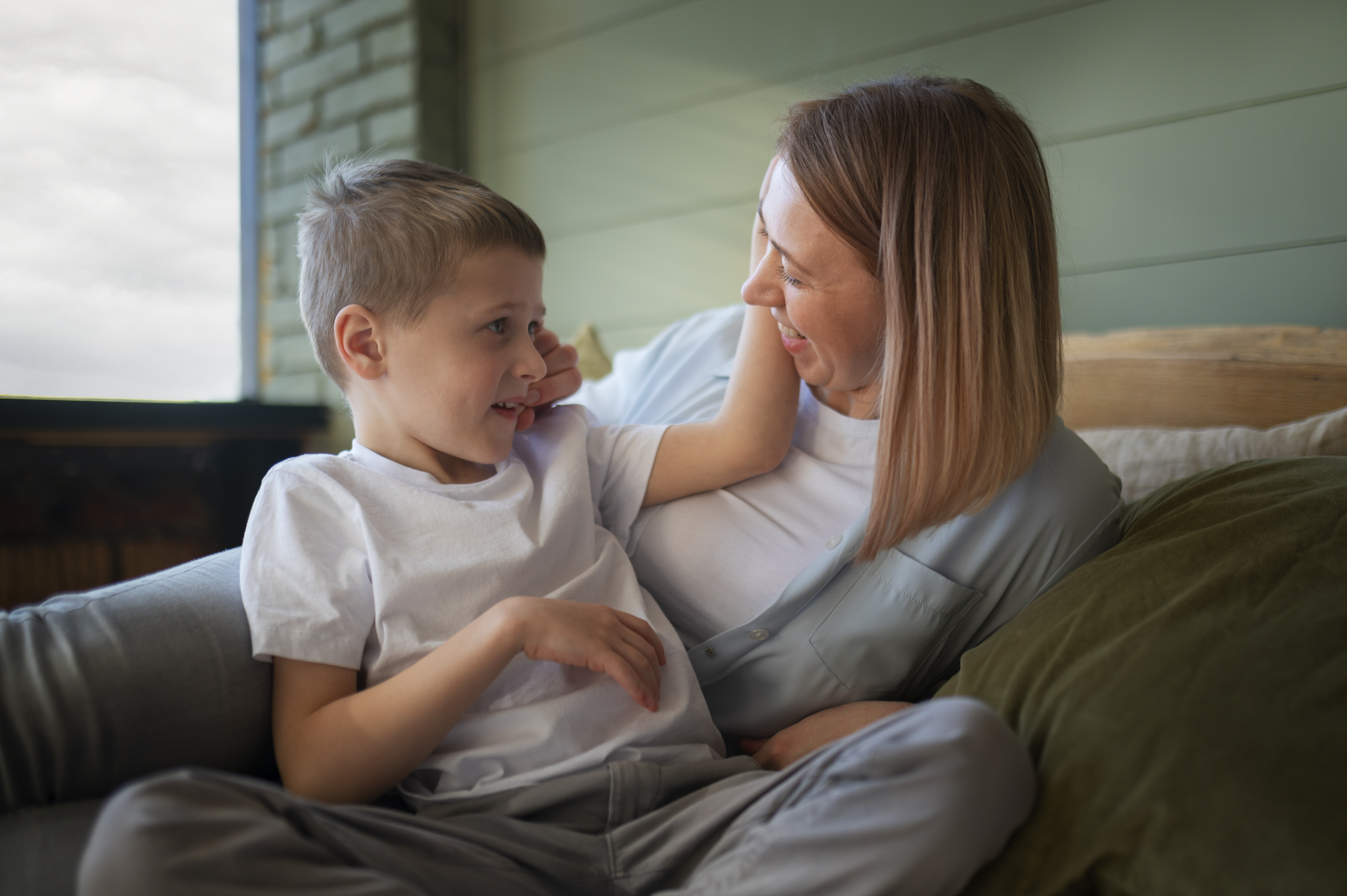 Niño pequeño siendo abrazado por su cuidador mientras le habla a la altura de los ojos Niño pequeño siendo abrazado por su cuidador mientras le habla a la altura de los ojos